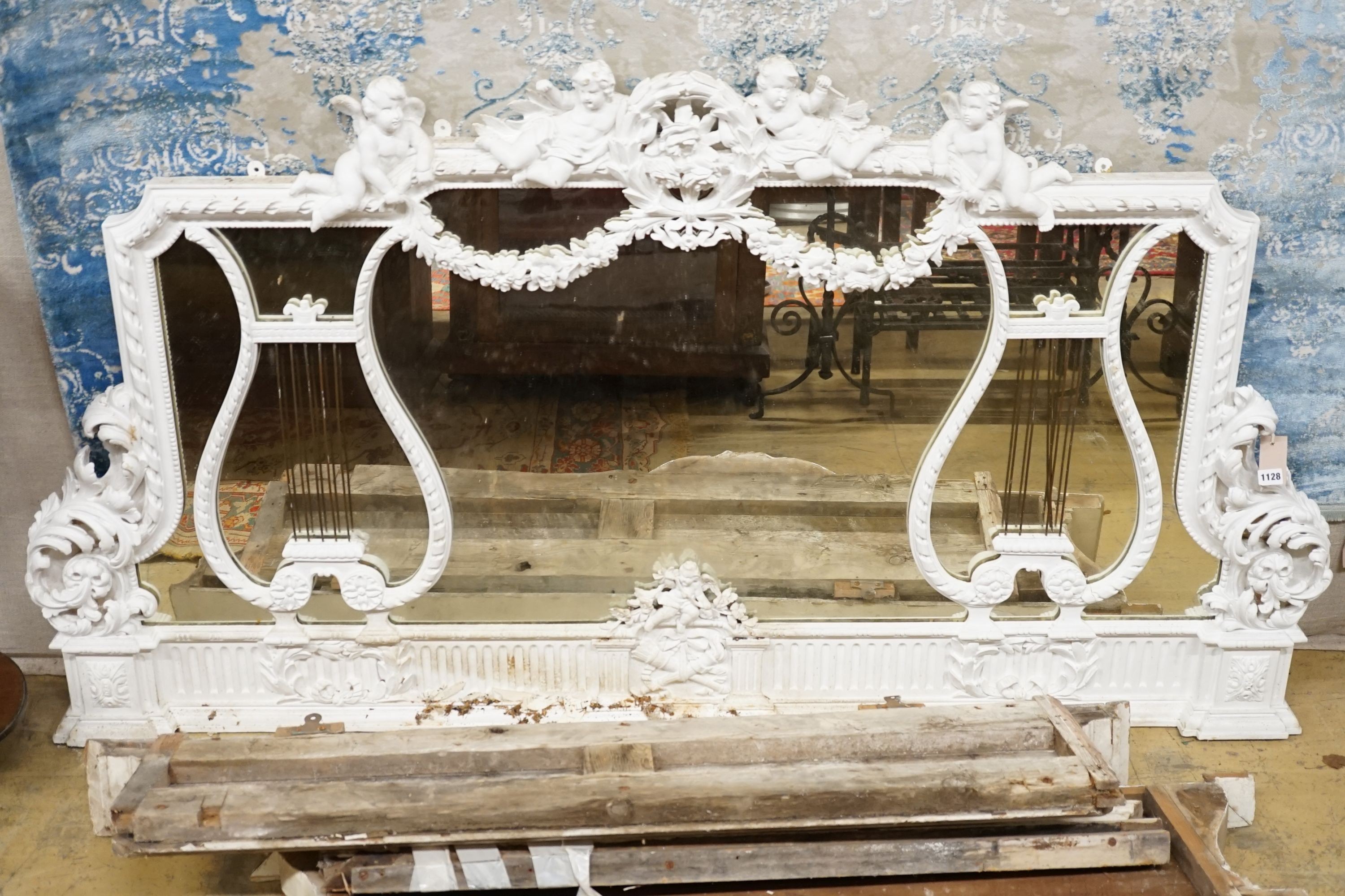 An Edwardian carved wood and gesso overmantel with cherub surmount, later painted white, width 188cm, height 96cm and a two white painted door pediments in need of restoration